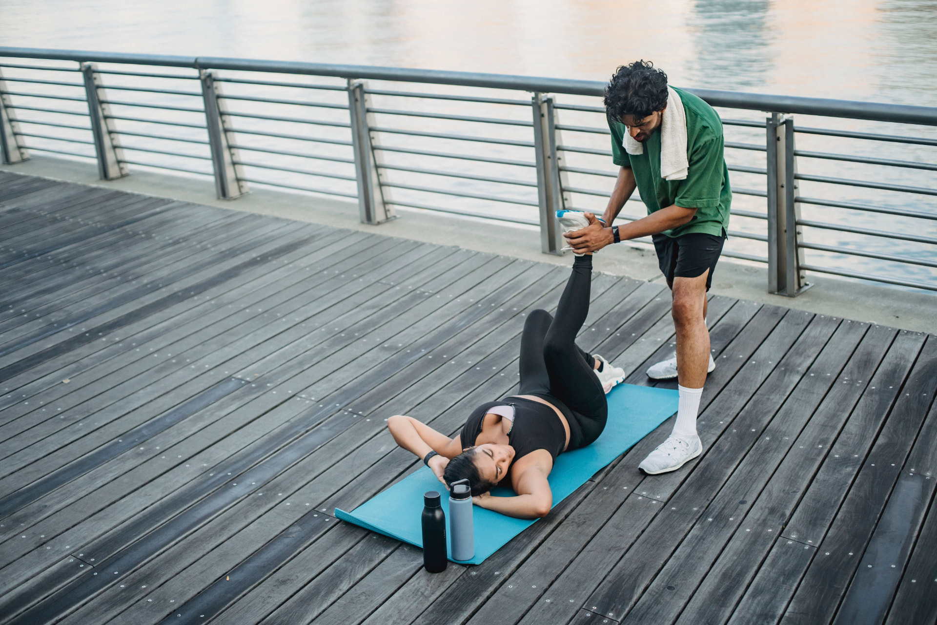 Une personne s’étire sur un tapis en extérieur pendant un exercice de mobilité accompagné