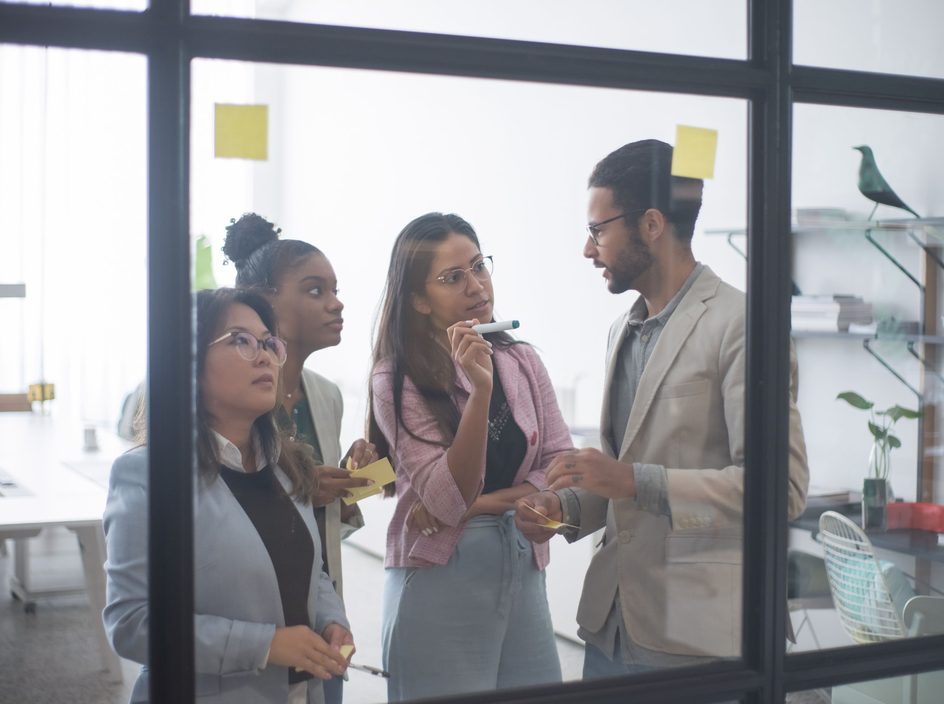 Une équipe de salariés collabore autour d'un tableau blanc dans un bureau lumineux